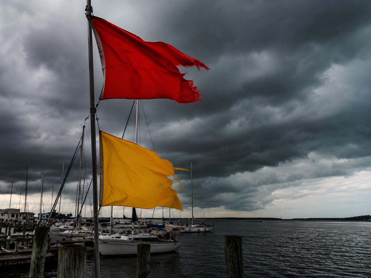 Weather warning flags at a harbor under storm clouds